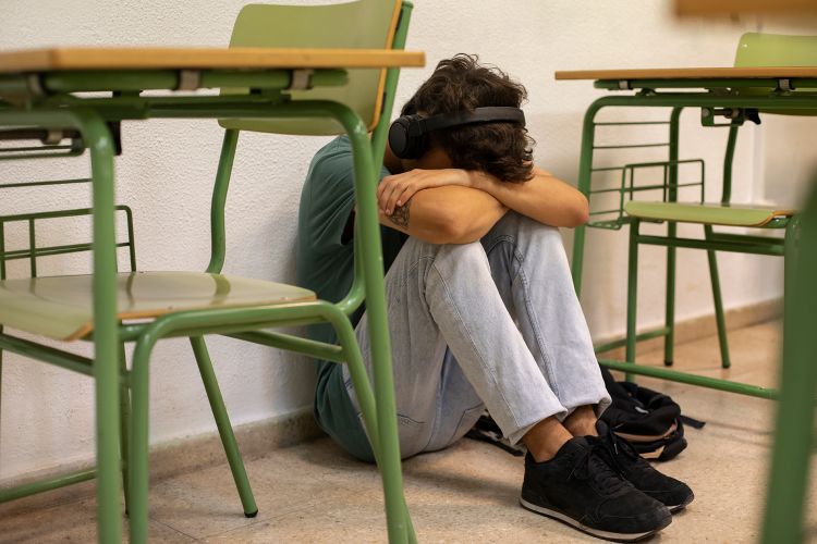 chico llorando con los cascos en clase